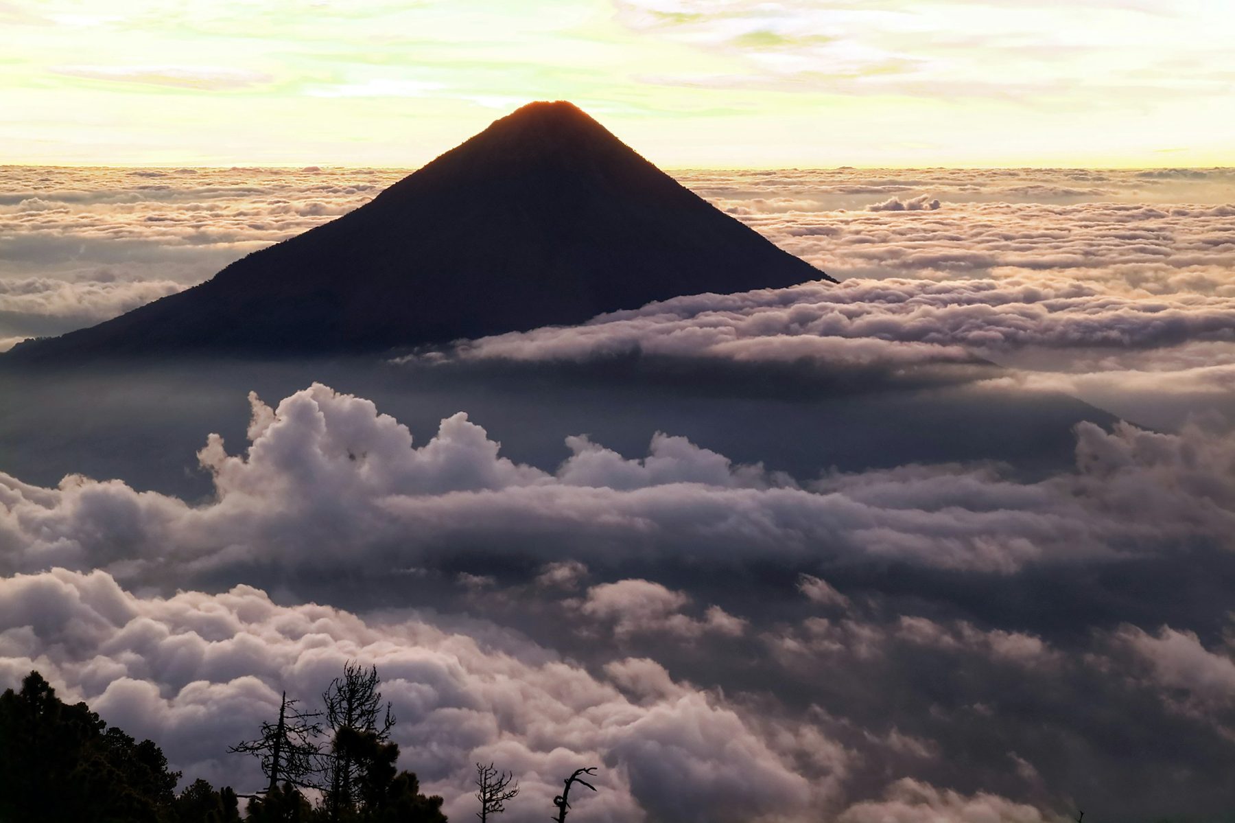 A volcano peak standing above a sea of cloud at sunrise, seen from Acatenango