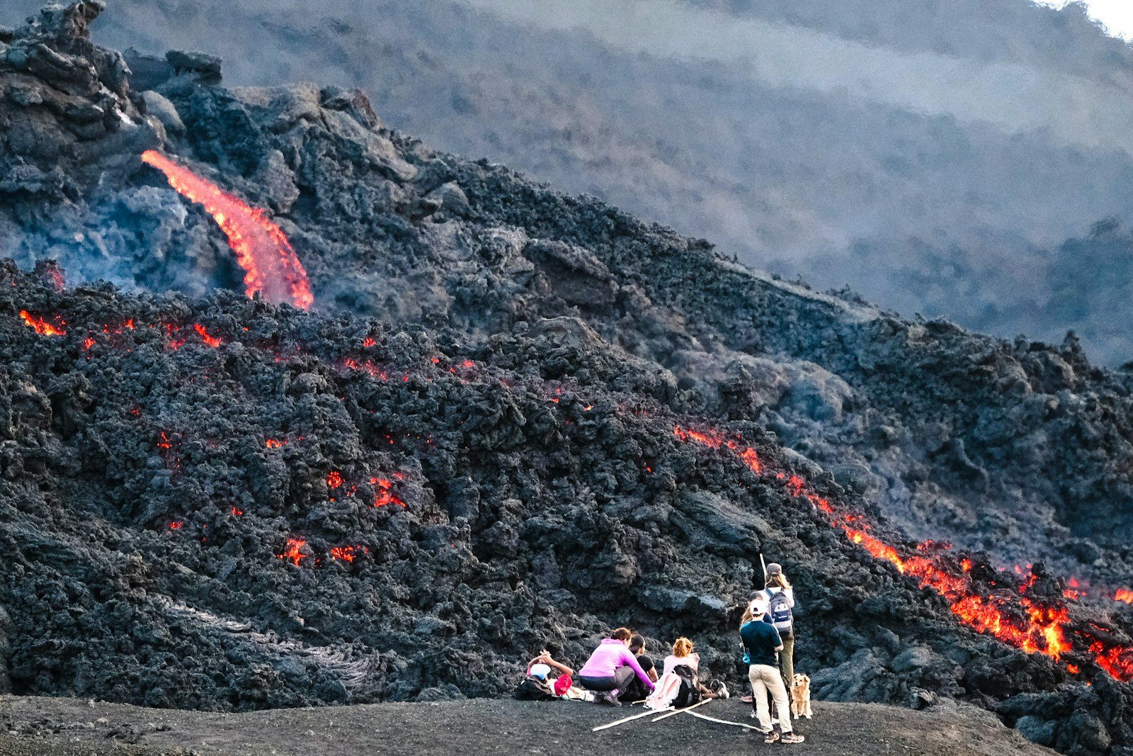 Walkers beside glowing lava on the slopes of Pacaya volcano